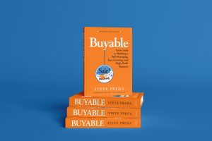 An orange colored book sits on top of three other orange books in front of a blue background. The title of the book is Buyable by Steve Preda